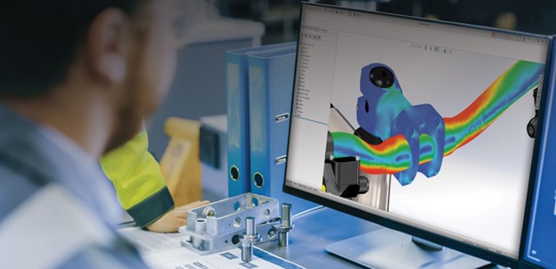 An engineer views a stress analysis on a computer screen, showcasing a 3D model of a mechanical part with color-coded stress distribution.