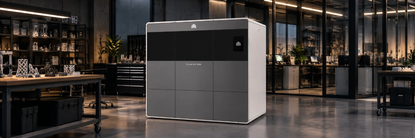 3D Systems ProJet MJP 5600 MultiJet 3D printer in a production lab, shelves of printed lattice parts on the left and glass-walled offices behind